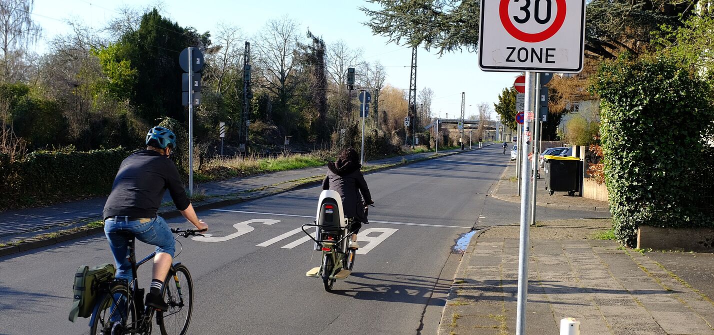 Zwei Radfahrer fahren an einem Tempo 30 Schild vorbei. 