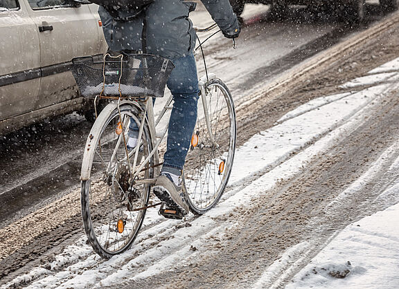 Ein Radfahrer fährt auf einem ungeräumten Radweg durch Schnee.