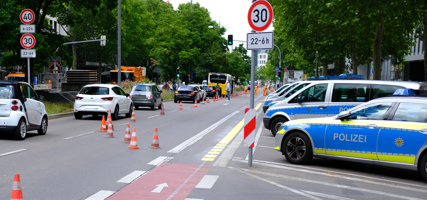 Ein schmaler Radfahrstreifen an einer viel befahrenen Straße. Die Verkehrssituation scheint wenig übersichtlich zu sein. 