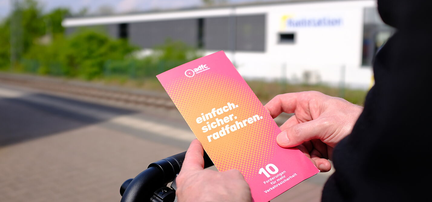 Eine Person hält einen Flyer in den Händen.