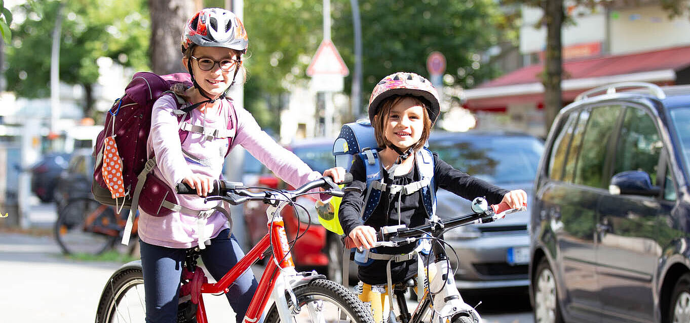 Mädchen mit Ranzen auf dem Fahrrad.